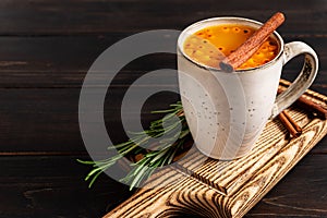 A cup of sea buckthorn hot drink on dark wooden background, copy space