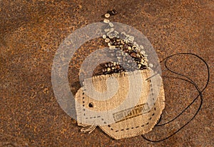 A cup sewn in jute full of coffee beans.