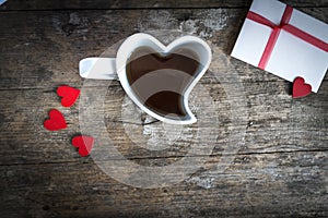 Cup in the shape of a heart and love letter on wooden table