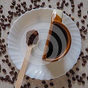 The Cup is shaped like a half on a white plate and coffee beans are scattered around