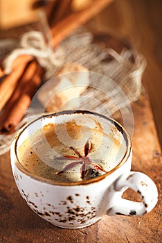 A cup of spiced coffee with anis star and cinamon sticks and sugar