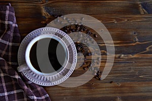 Cup of strong black coffee with coffee beans on wooden background