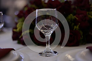 Cup on the table with white lining, red flower arrangement on blurred background