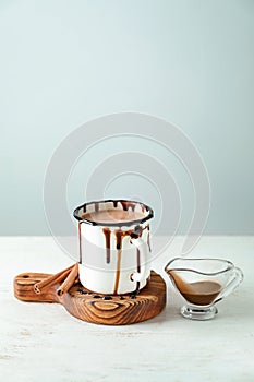 Cup of tasty cocoa and sauce boat on white table