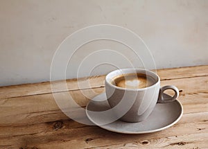 Cup of tasty coffee with heart shaped milk foam on wooden cafe table