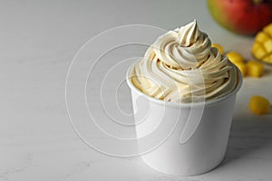 Cup with tasty frozen yogurt on light wooden table