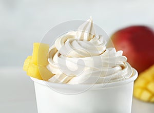 Cup with tasty frozen yogurt with mango on background, closeup