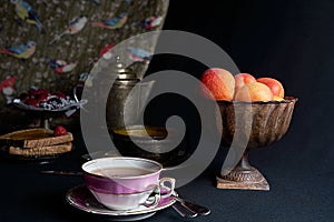 A cup of tea accompanied by fresh apricots, apricot jam and a tray of berries photo
