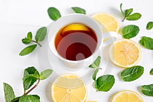A cup of tea along with mint and lemon. Cold tea. Natural cures for the disease. Vitamin C. Black tea with lemon on a white