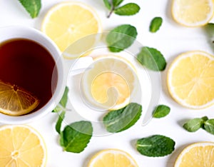 A cup of tea along with mint and lemon. Cold tea. Natural cures for the disease. Vitamin C. Black tea with lemon on a white