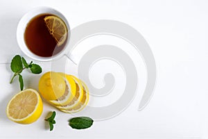 A cup of tea along with mint and lemon. Tea for colds. Natural cures for the disease. Vitamin C. Black tea with lemon on a white