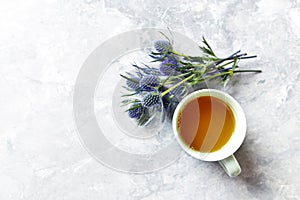 Cup of Tea and Amethyst Sea Holly Flowers on gray background