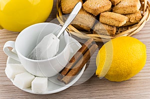 Cup with tea bag, sugar and cinnamon, lemon and cookies