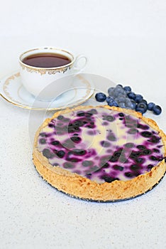 Cup of tea and blueberry pie on a white background - vertical.