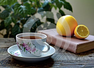 Cup of tea, book, fruits on wood table