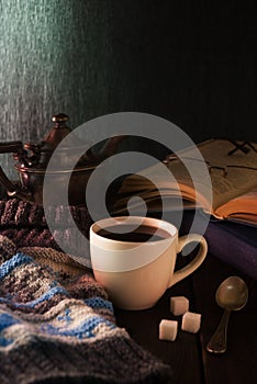 Cup of tea, book and knit cap on wooden table