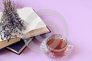 A cup of tea, a bouquet of lavender on an open book on a pastel background, side view, space for text