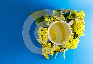 Cup of tea in braided wicker basket filled with lime blossom