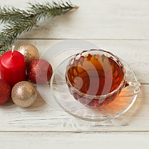 A cup of tea, a branch of a Christmas tree and decor on a light wooden background. Christmas composition