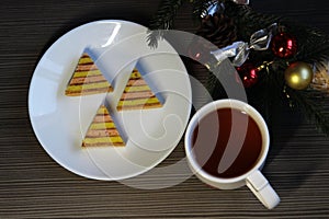 A cup of tea, a branch of a Christmas tree decorated with red and yellow balls