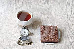 Cup of tea with brownies and clock is four o`clock