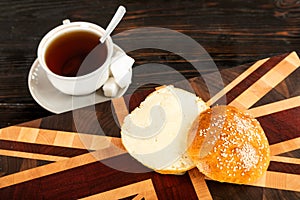 Cup of tea and a bun on a cutting board