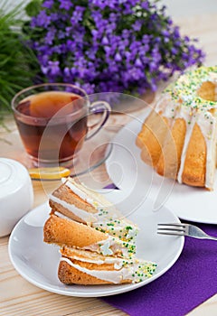 Cup of tea and cake on porcelain tableware on the purple tablecloth