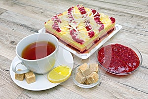 Cup with tea, cake and raspberry jam on a wooden table