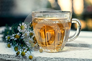 A Cup of tea with chamomile on a wooden background.