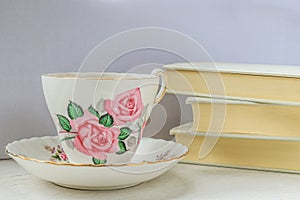 Cup of tea in a china cup and saucer and stack of books