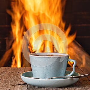 A cup with tea or coffee near a cozy fireplace, in a country house