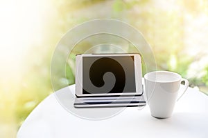 Cup of tea or coffee and tablet empty screen digital on table on