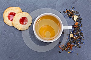 Cup of tea with cookies, sugar and loose leaves