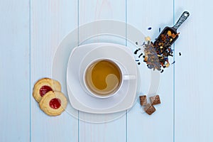 Cup of tea with cookies, sugar and loose leaves