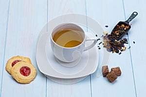 Cup of tea with cookies, sugar and loose leaves