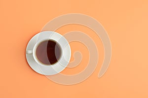 Cup of tea on coral background, top view