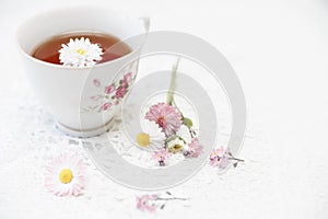 Cup of tea with daisies on white background