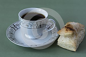 Cup of tea on a dish and a puff pastry