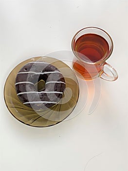Cup of tea and donut in chocolate on a saucer, on a white background