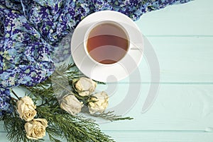 Cup of tea with dried roses and branches of juniper