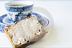 Cup of tea with Dutch spiced bread called Ontbijtkoek or Peperkoek. On white table