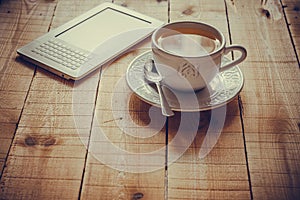 A cup of tea and an ebook reader on a wood table