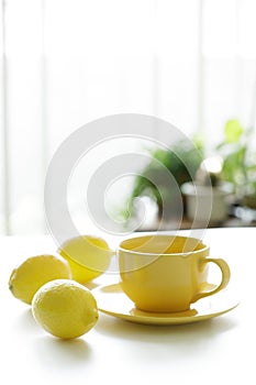 Cup of tea with fresh yellow lemons on white background