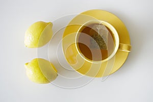 Cup of tea with fresh yellow lemons on white background
