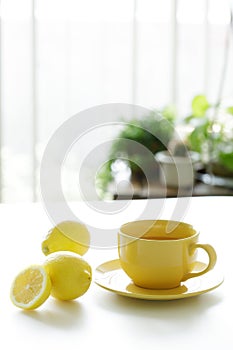 Cup of tea with fresh yellow lemons on white background