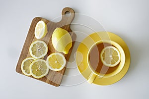 Cup of tea with fresh yellow lemons on white background