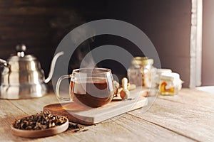 Cup or tea glass Hot brew and dried tea leaves on a wooden plate, placed on a wooden table, on a dark black background