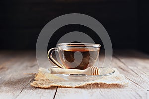 Cup or tea glass Hot brew and dried tea leaves on a wooden plate, placed on a wooden table, on a dark black background