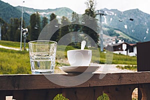 Cup of tea and a glass of water on a terrace on the porch curb against the backdrop mountains ski resort