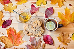 Cup of tea, honey, cookies and autumn leaves on wooden table. Top view